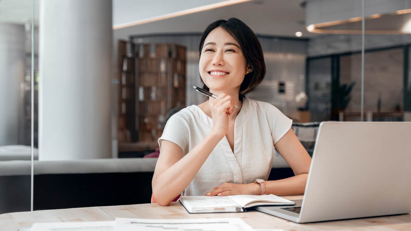 smiling young woman working on laptop at work