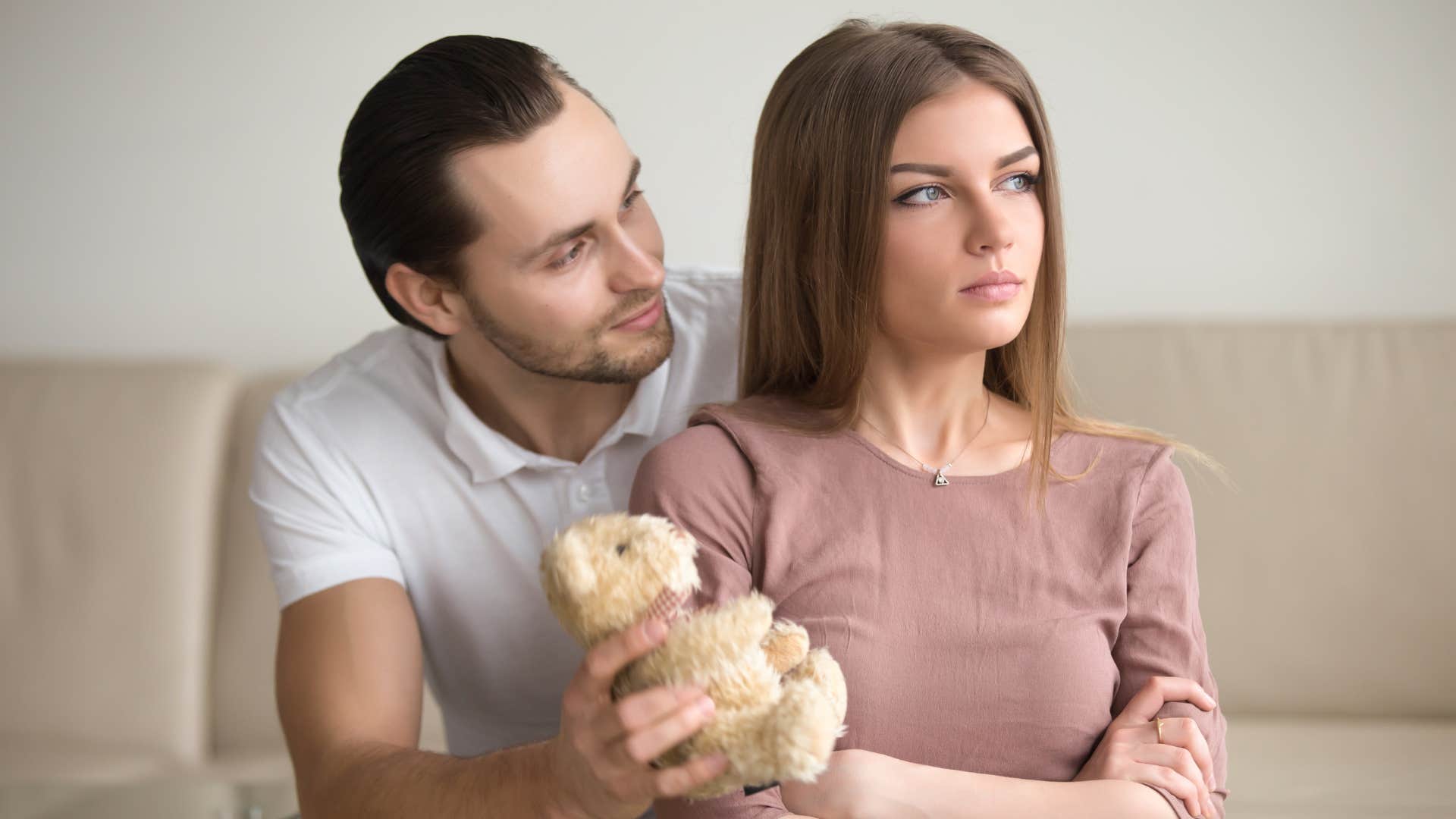 man giving upset woman a teddy bear