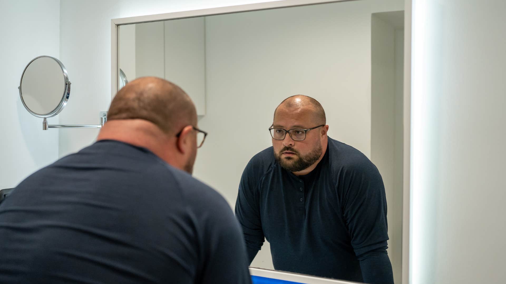 man engaging in negative self-talk in the mirror at home