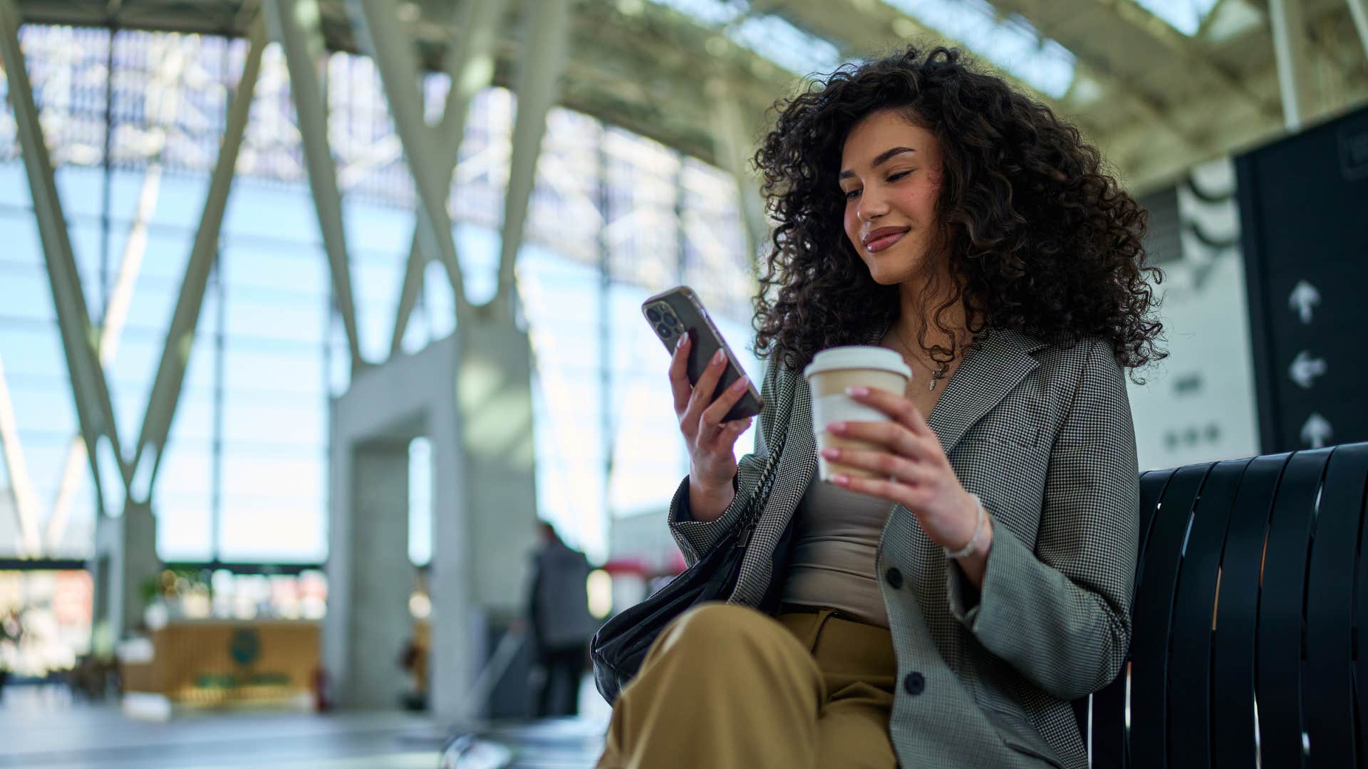 woman checking her phone sitting at airport