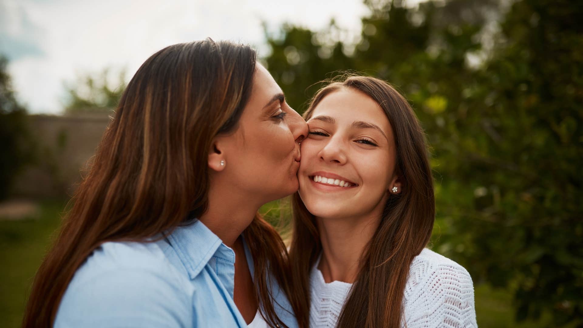mother kissing daughter's cheek 