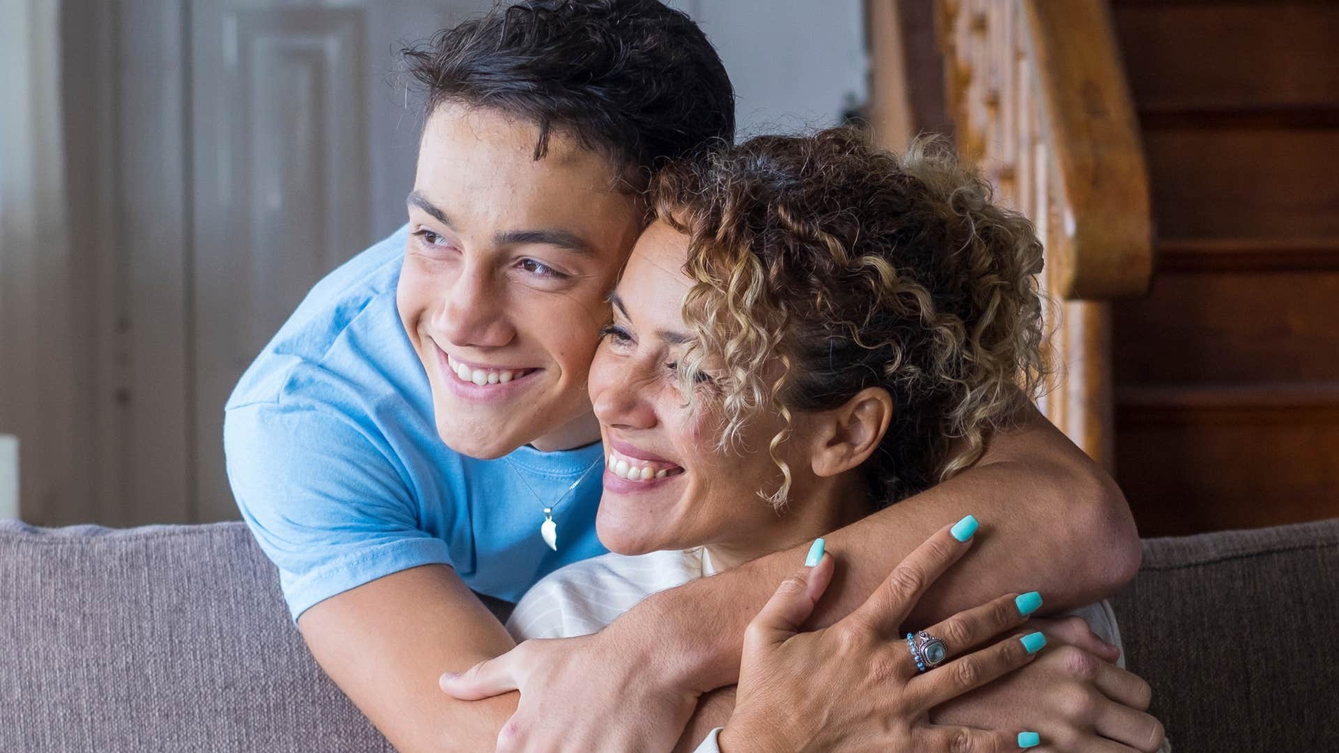 son hugging mom from behind lovingly