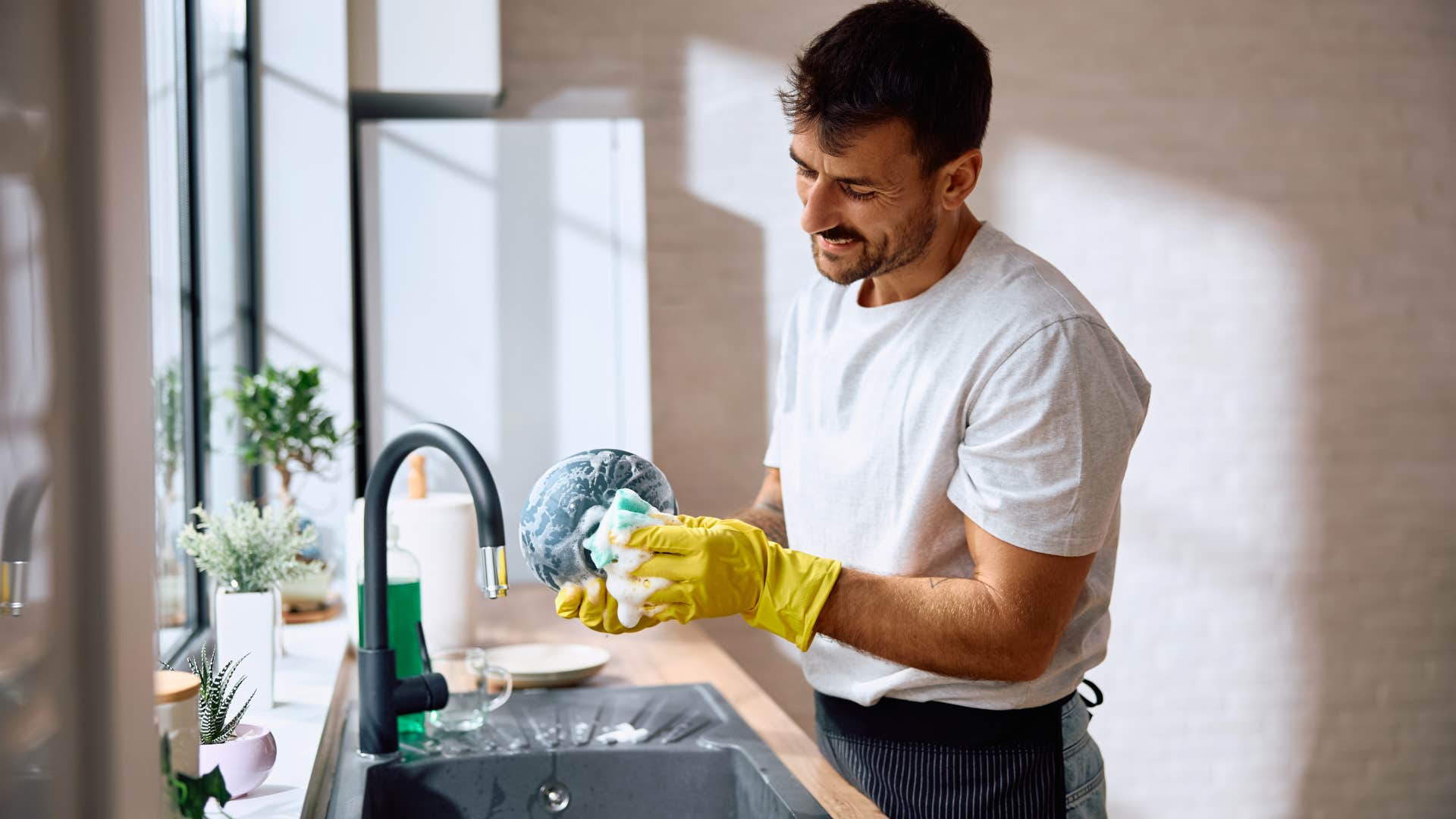 man washing dirty dishes in the sink