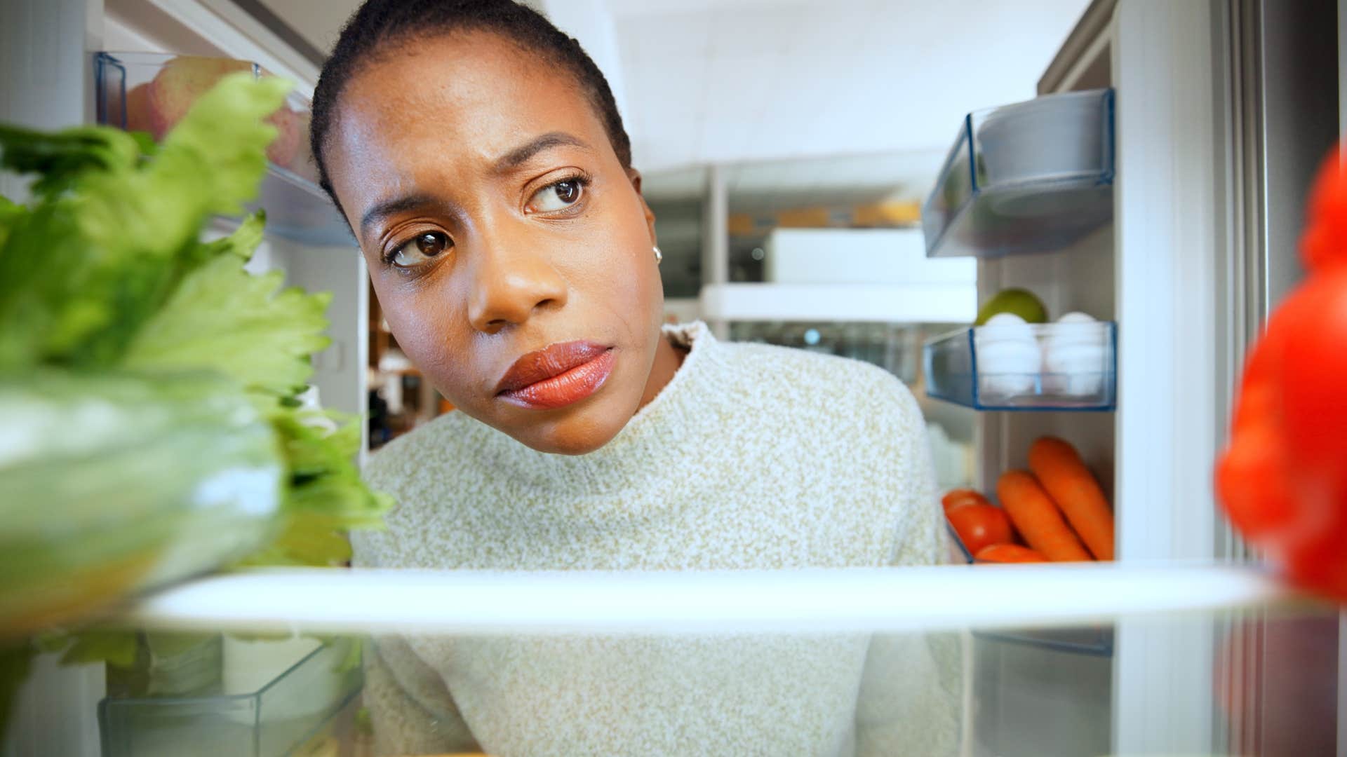 woman looking in fridge for expired food