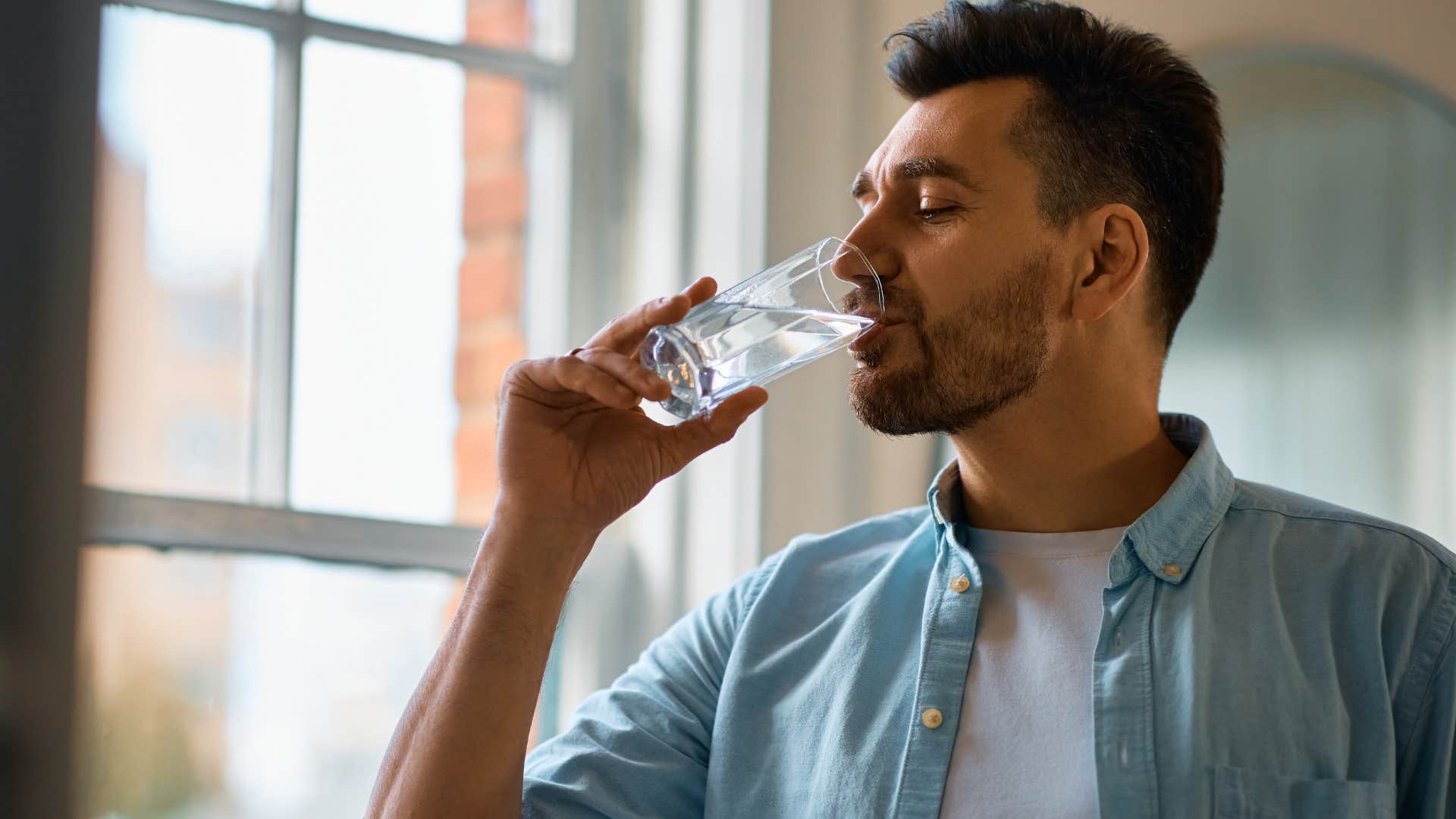 man taking his prescriptions with water