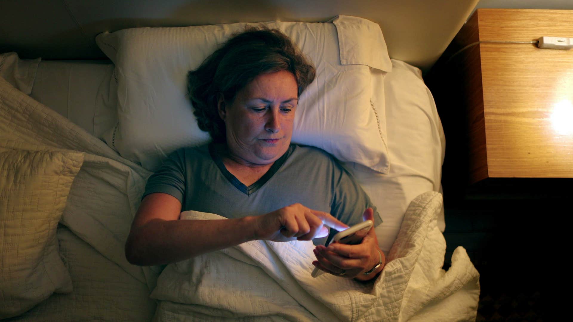 woman checking social media in bed