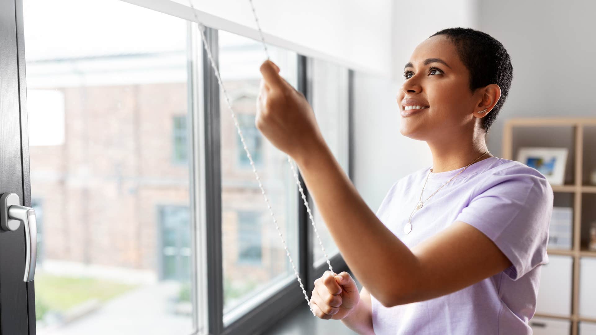woman opening up the blinds at home