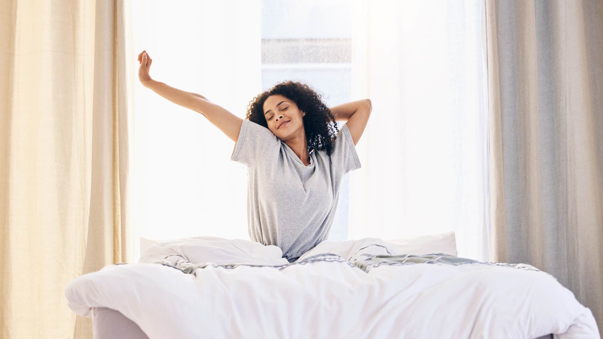 woman waking up in the morning smiling and stretching
