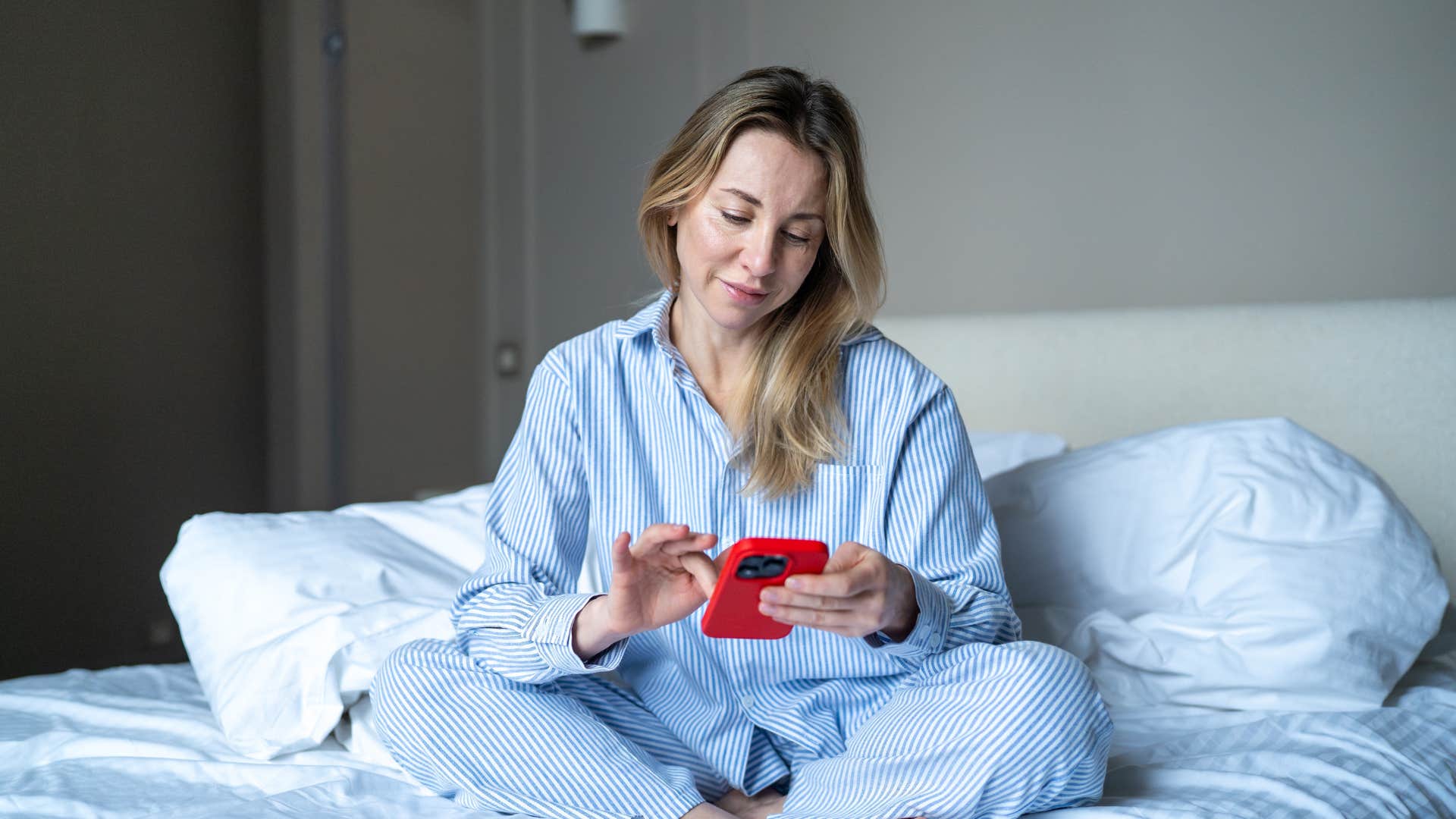 woman sitting in bed on her phone