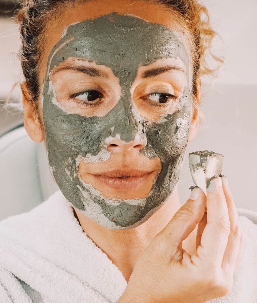 Woman applies cleansing face mask