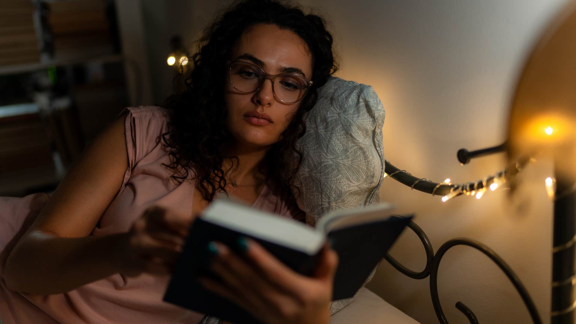 woman comfortable in bed reading a book