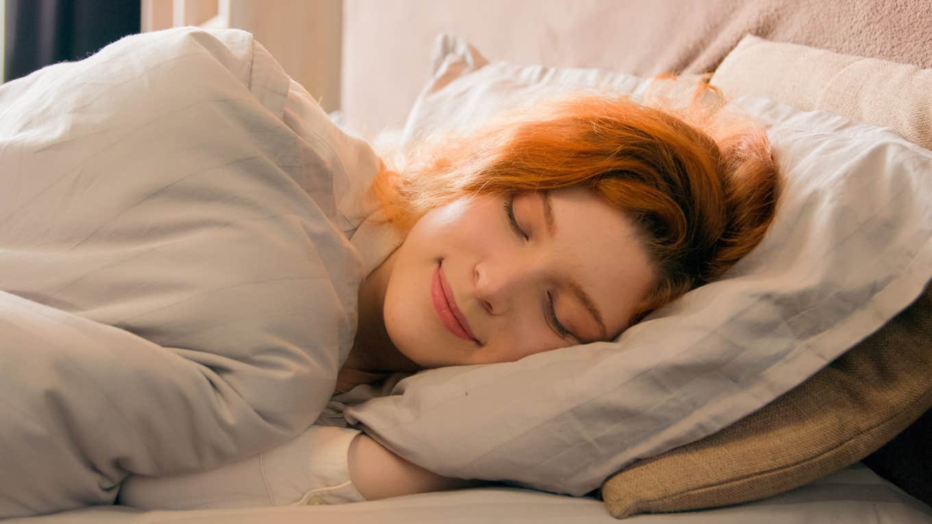 woman laying in bed cuddling her pillow to fall asleep