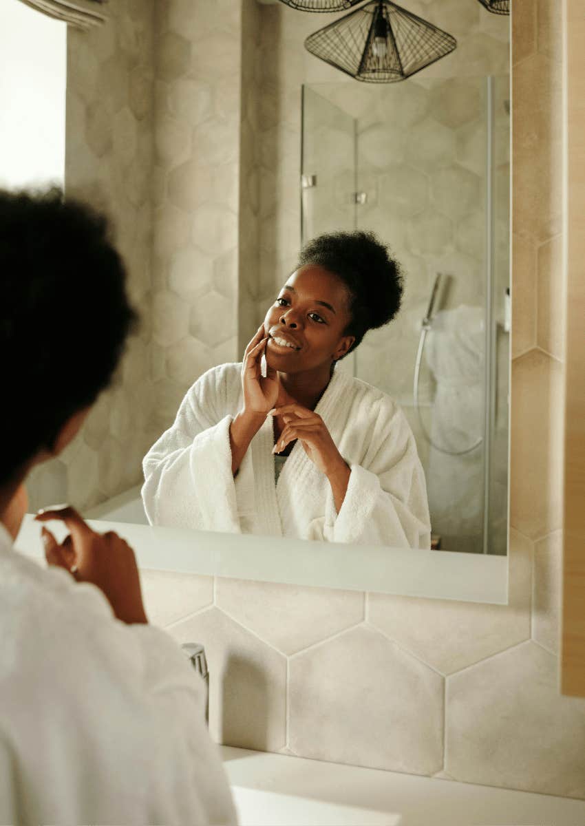 adult woman in a bathrobe staring at her reflection