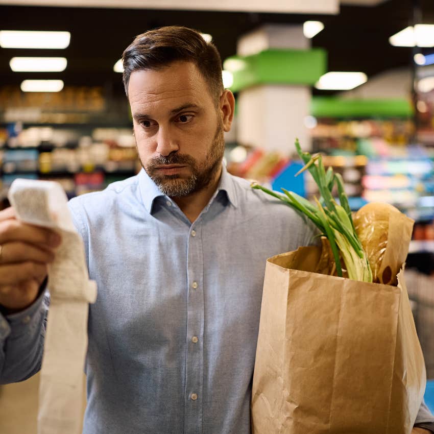 Man looking at his receipt stressed out about the cost of groceries