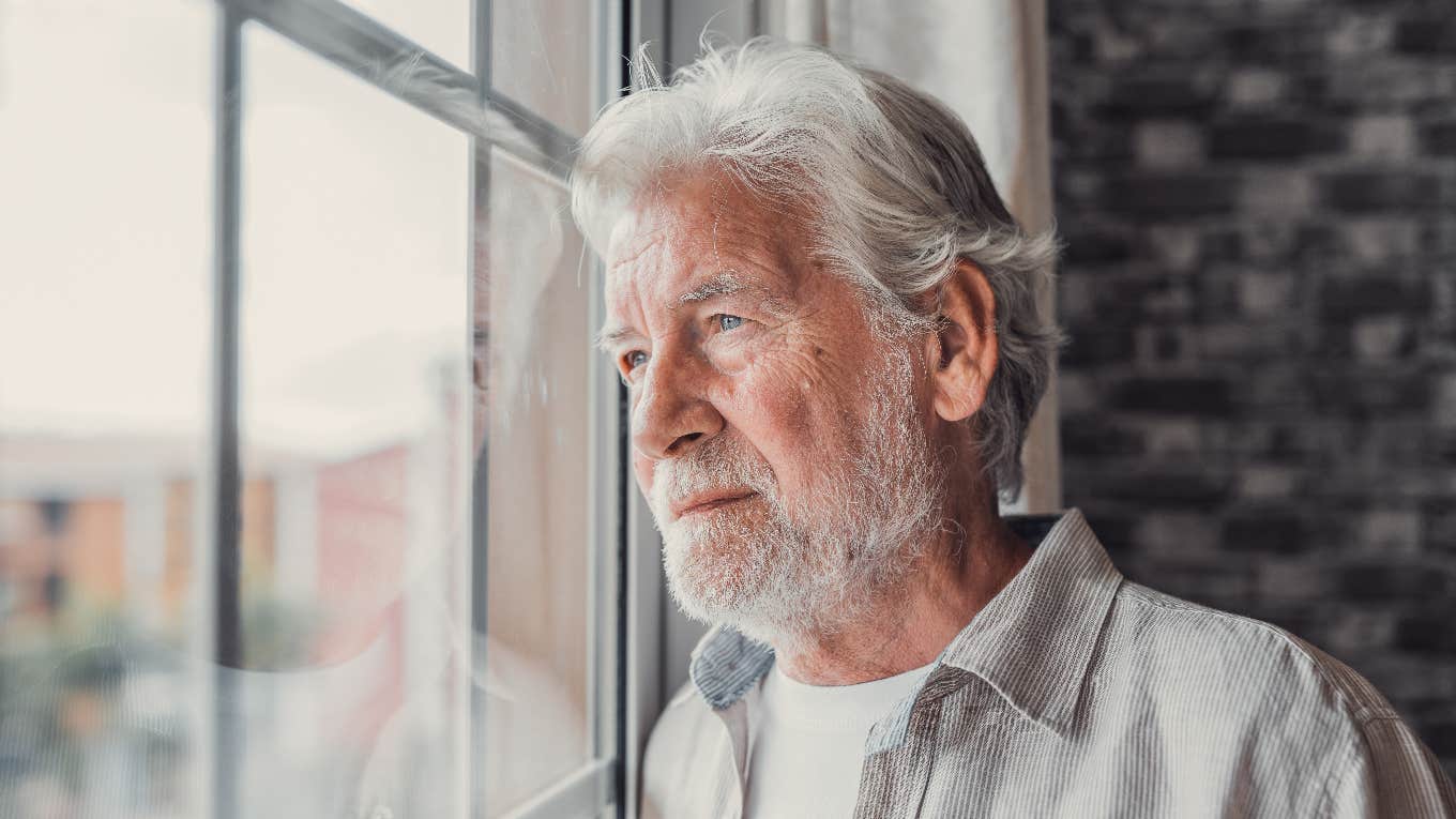 serious boomer man looking out window