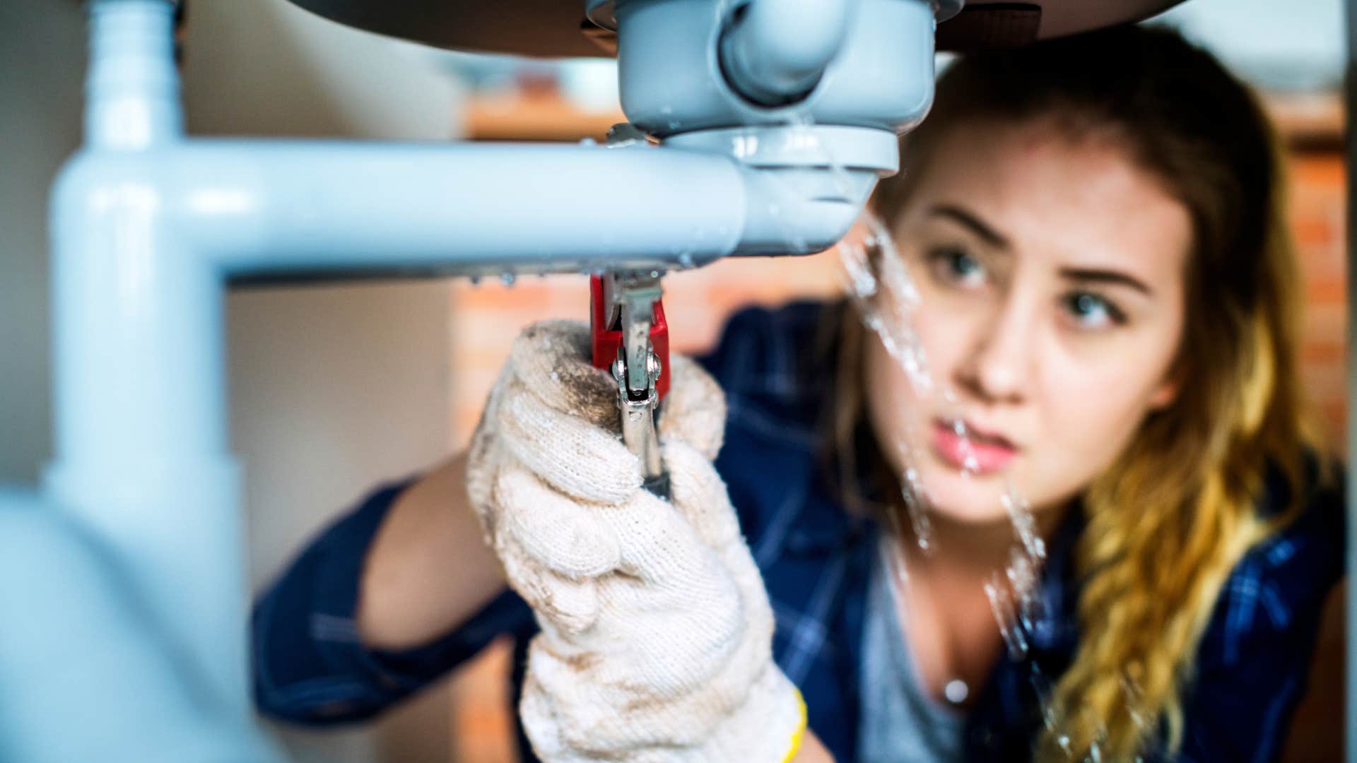 woman fixing pipe in broken sink before replacing it
