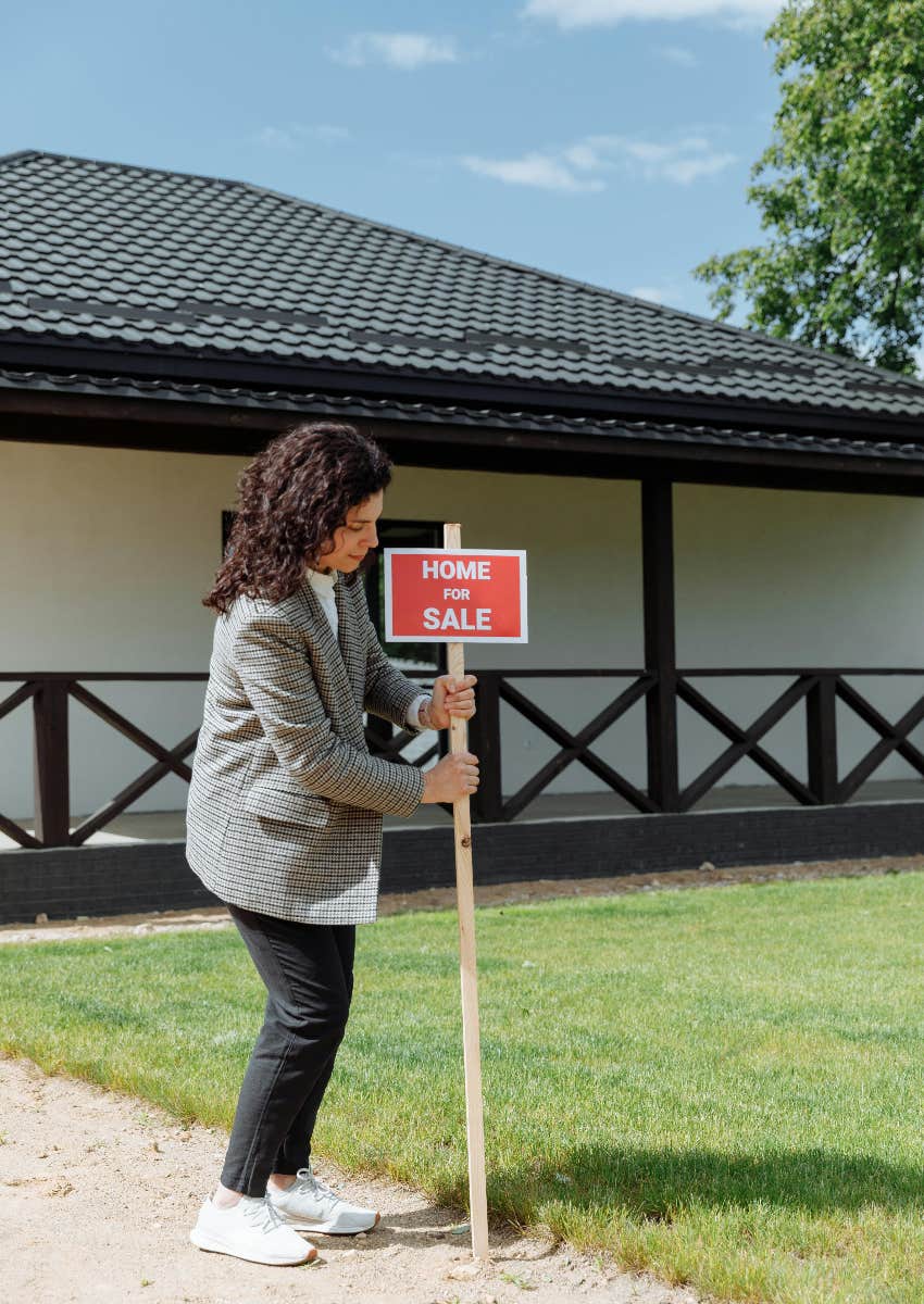 realtor putting for sale sign in front of home