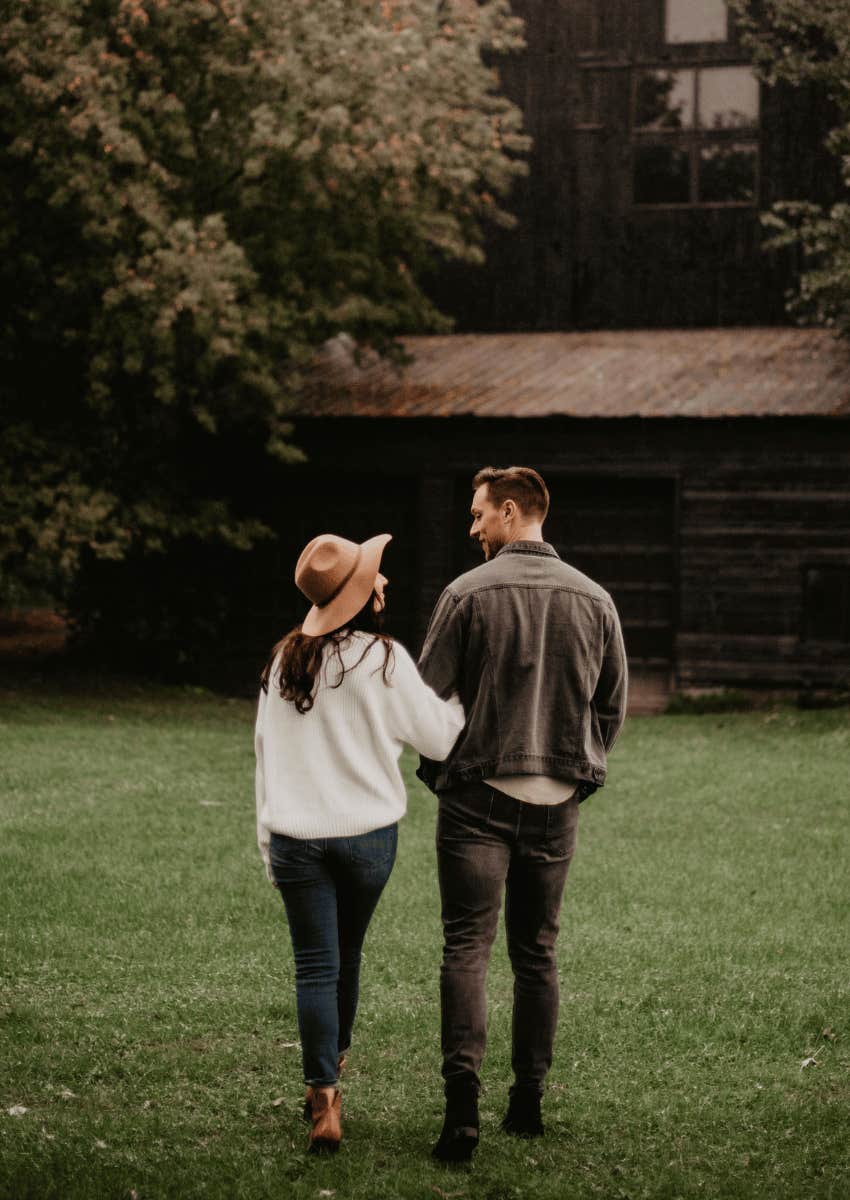 couple holding each other close walking in their backyard
