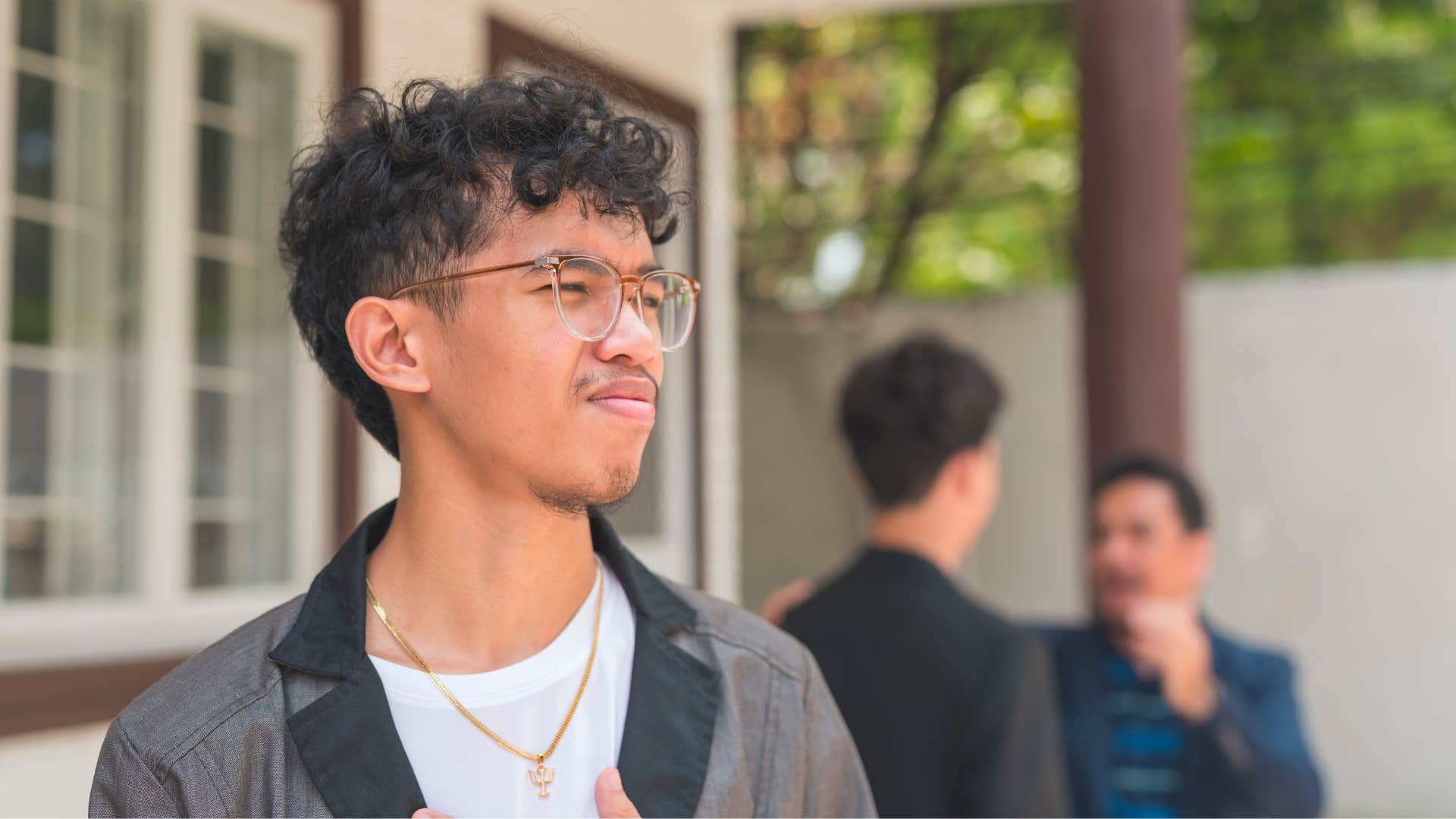 young man standing idly by while dad plays favorites with siblings