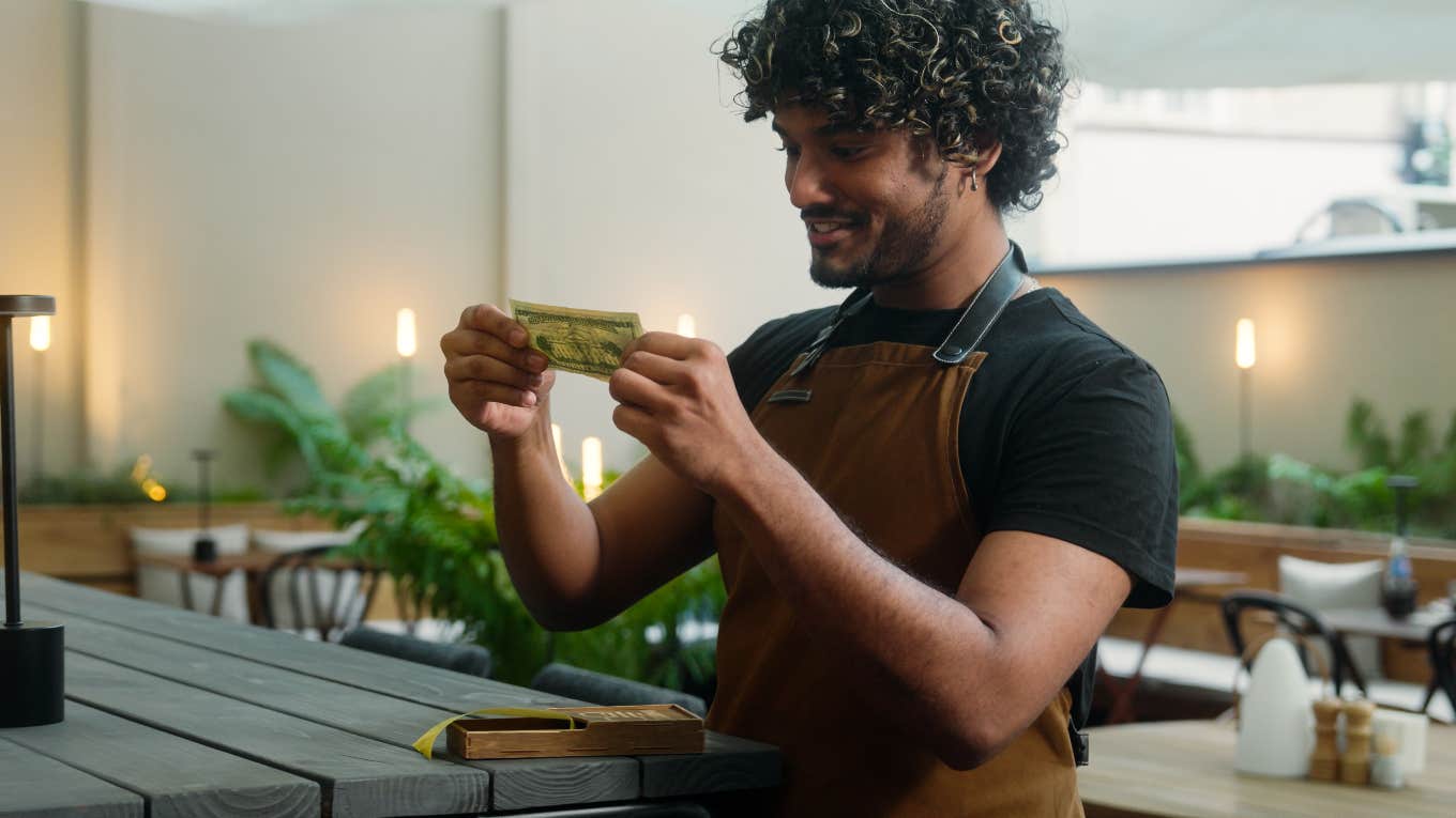 happy waiter receiving tip from customer