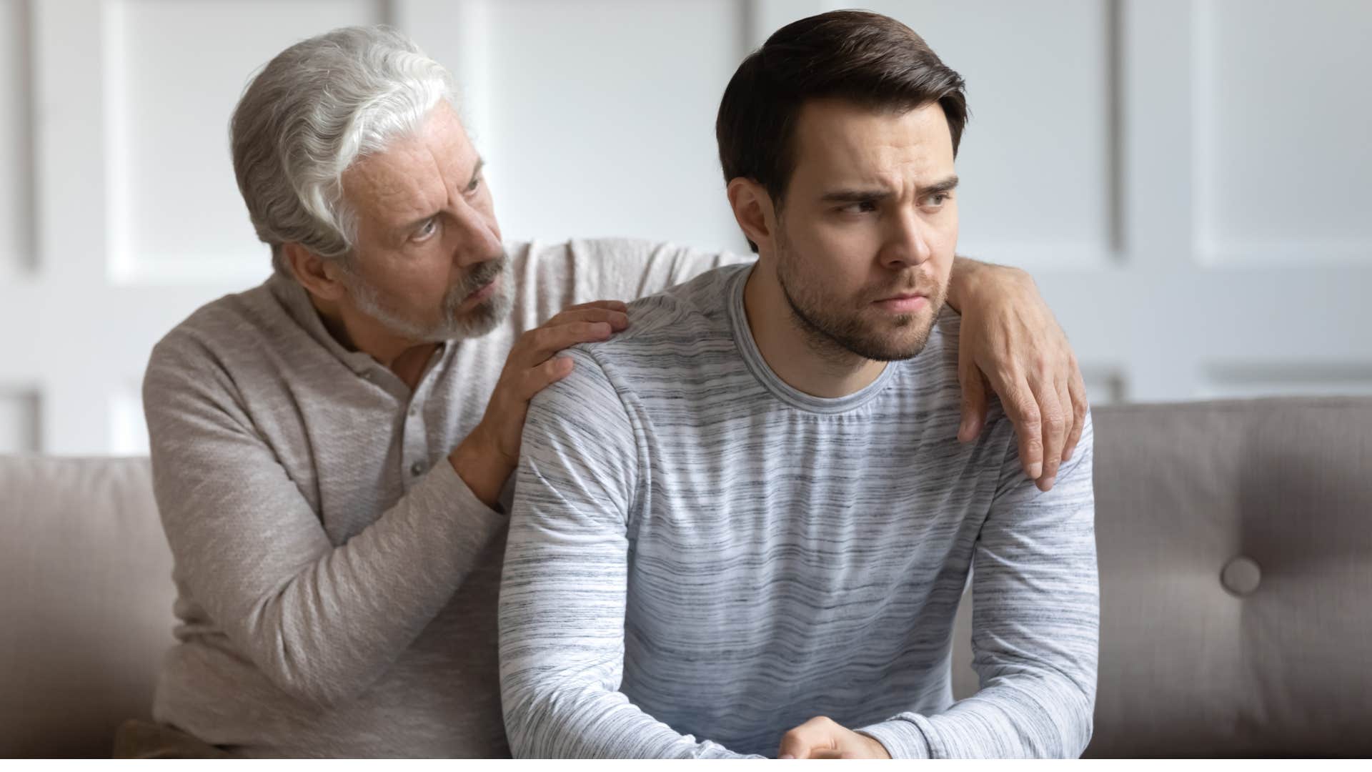 older father touching son's shoulders