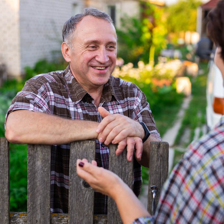 Man talking to neighbors over a fence at home.