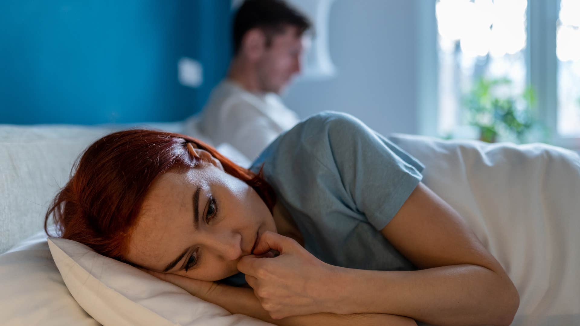 woman laying in bed next to husband who has stopped initiating conversations