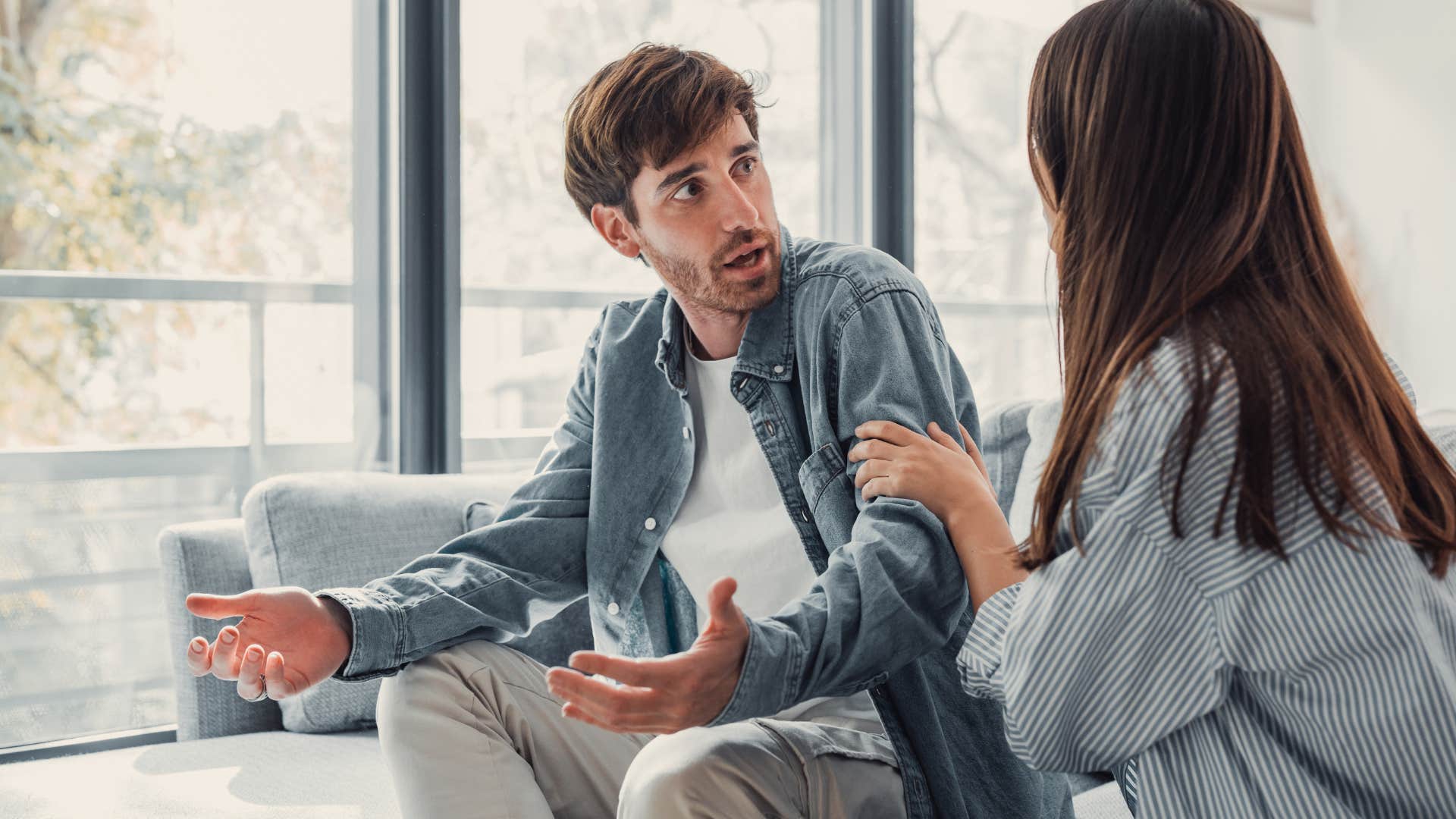man emotionally withdrawn as he argues with woman on couch