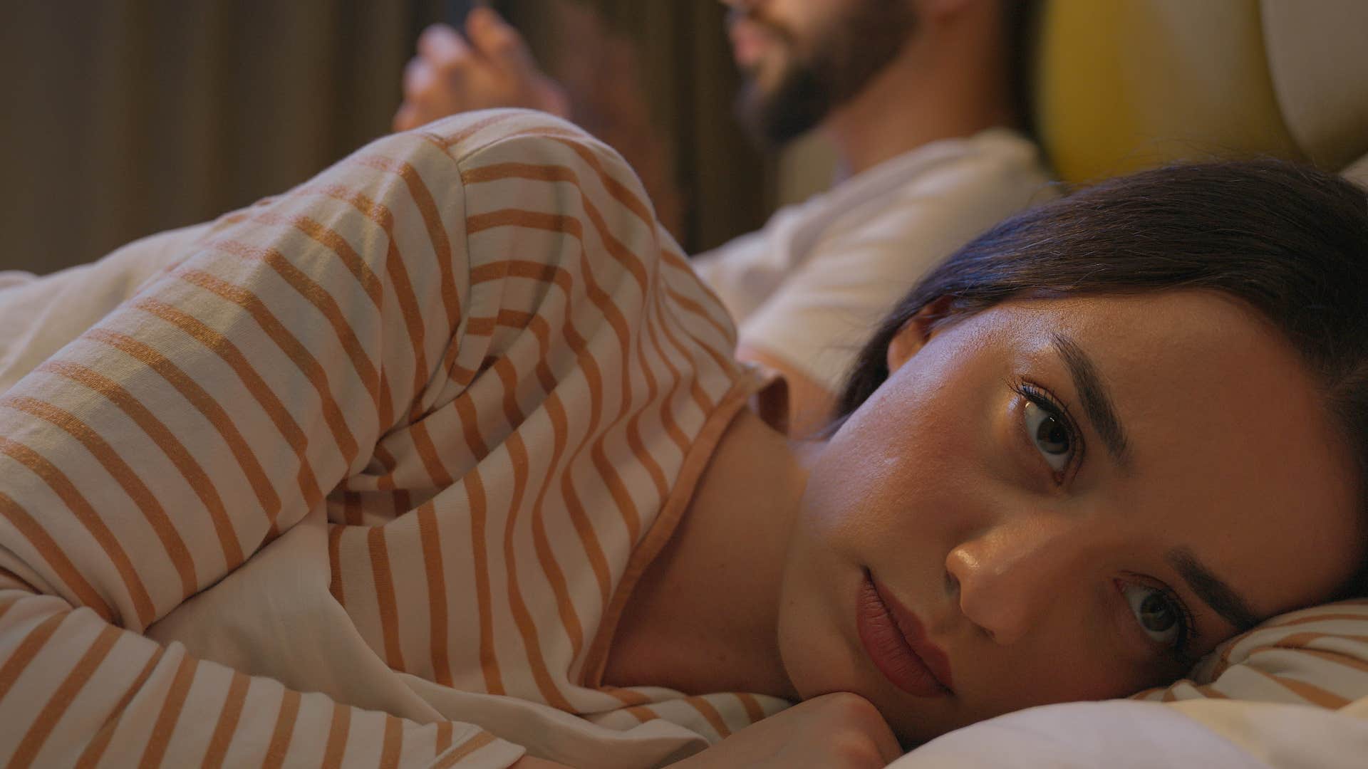 woman feeling loss of affection as man ignores her and goes on phone