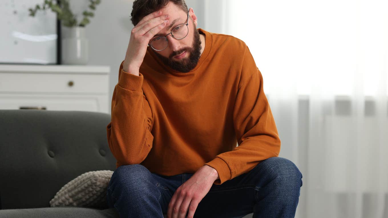 man sitting on couch feeling overwhelmed