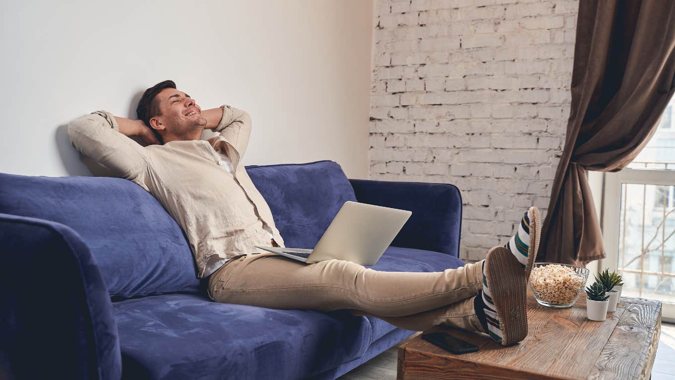 man relaxing on couch with laptop and popcorn