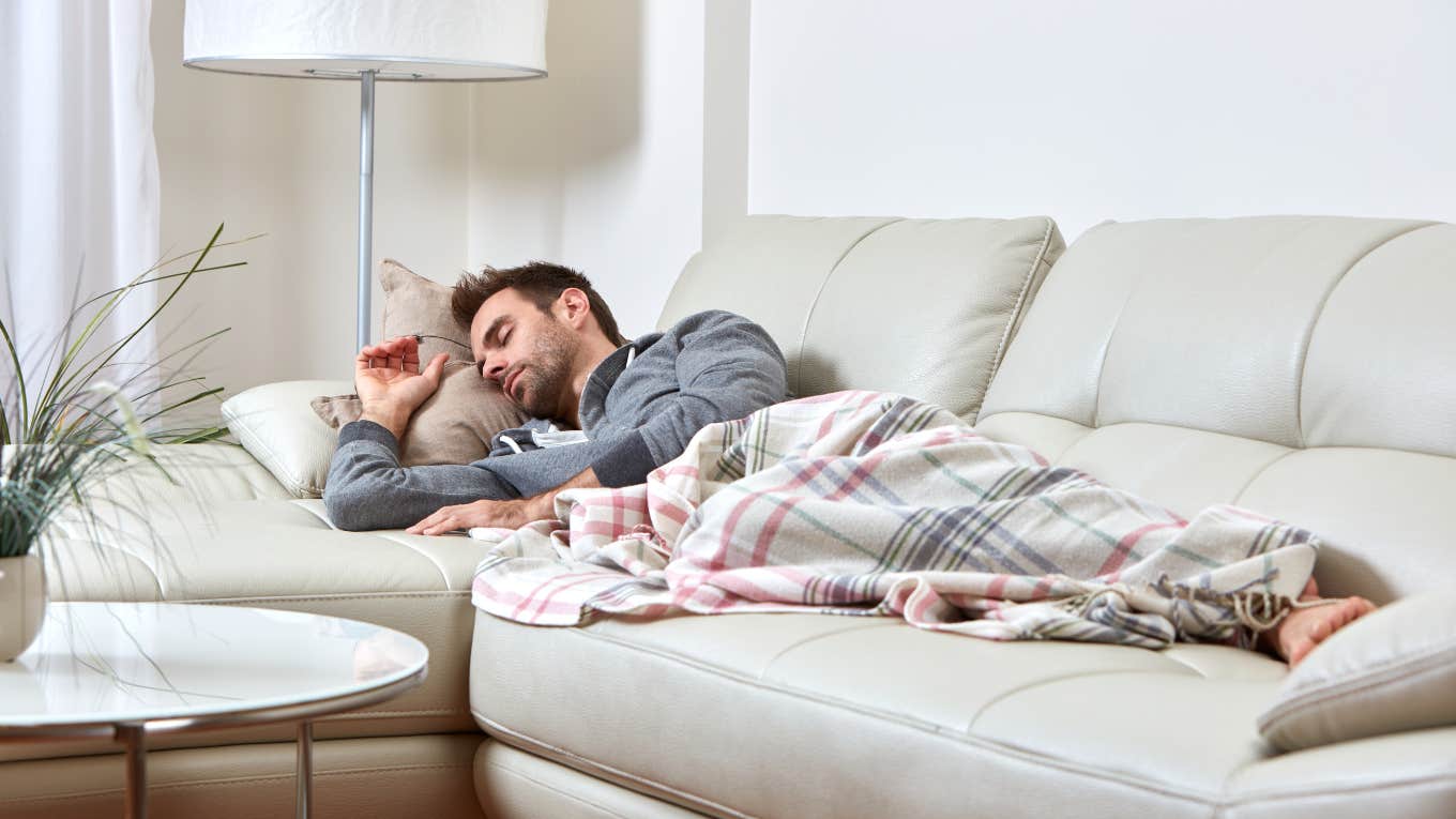 man sleeping on couch with blanket