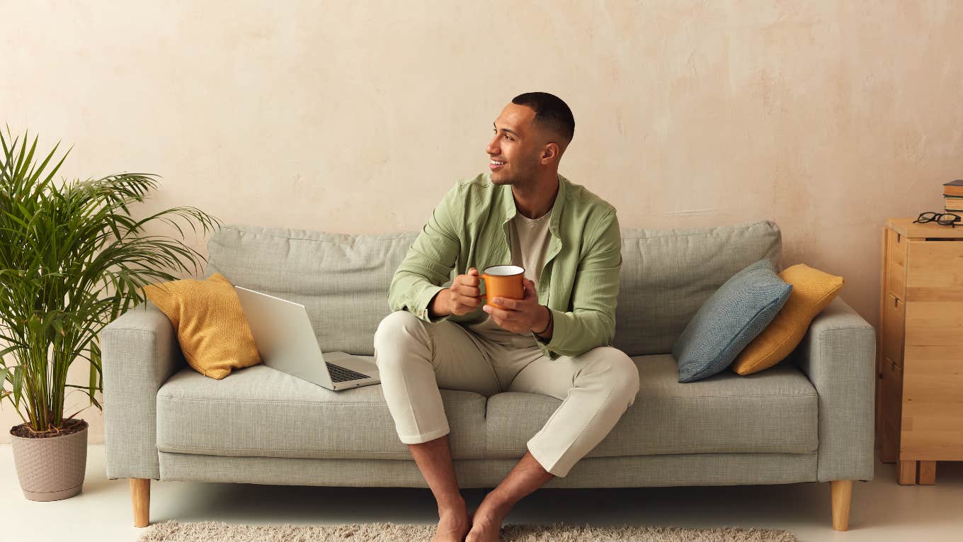 man relaxing on couch holding mug