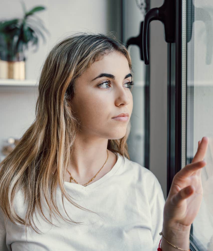 Suspicious woman looks out window showing her partner is probably going to cheat