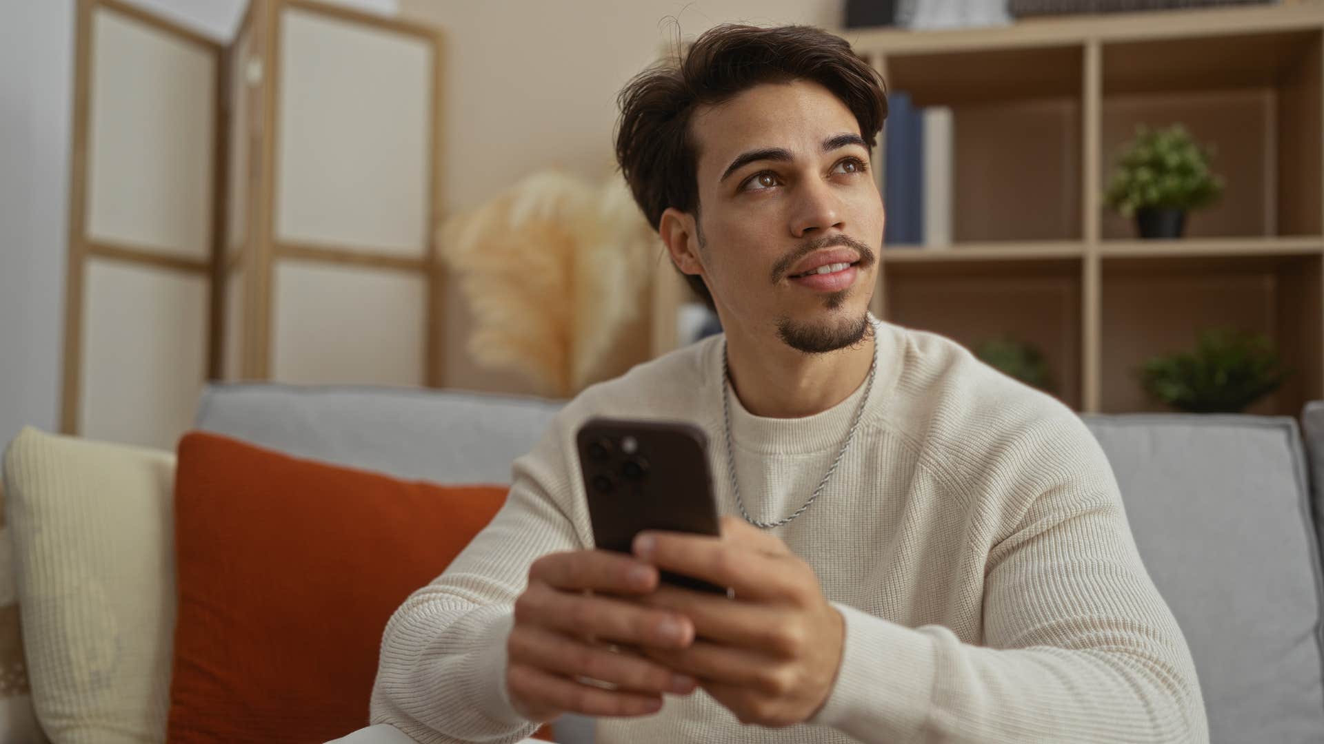 young man holding his phone looking off into distance
