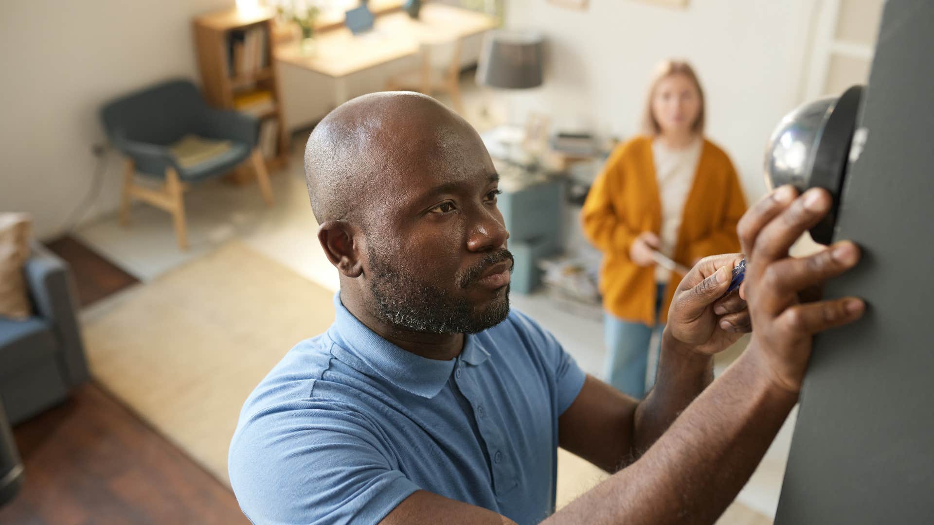 man fixing thermostat for wife