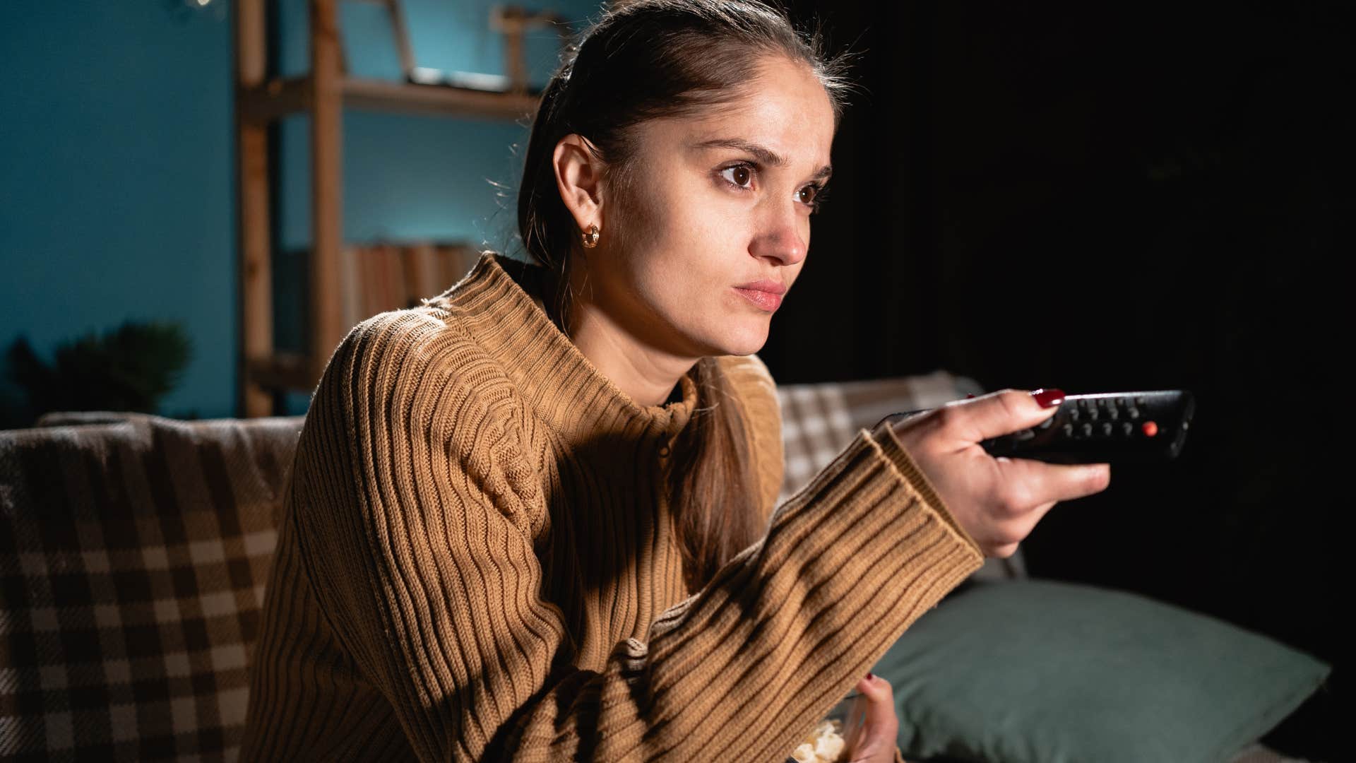 woman channel surfing because she finds stillness and quietness to be uncomfortable