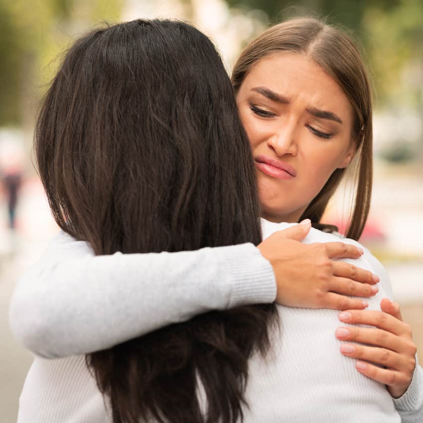 woman who feels pride in deceiving others hugging friend reluctantly