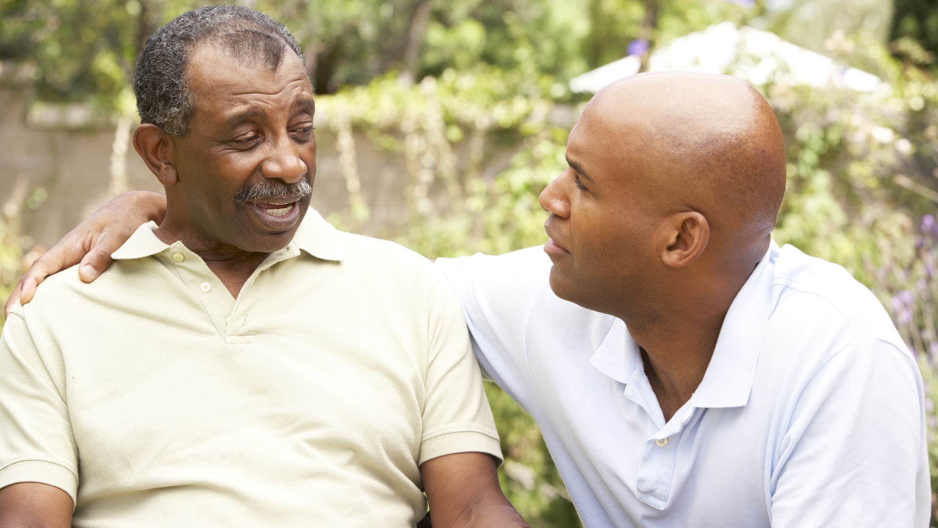 two men having serious conversation on park bench outside