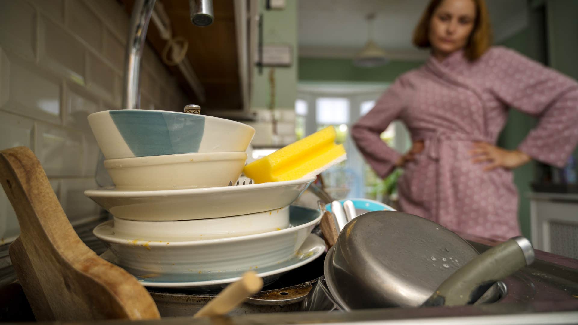 woman looking at pile of dirty dishes