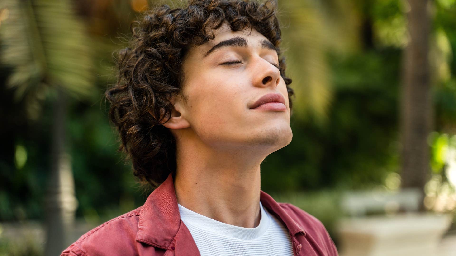 man with eyes closed standing outside