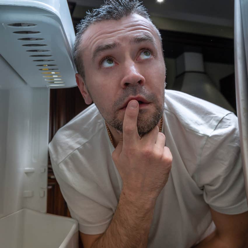 Man looking in a fridge of expired food at home.