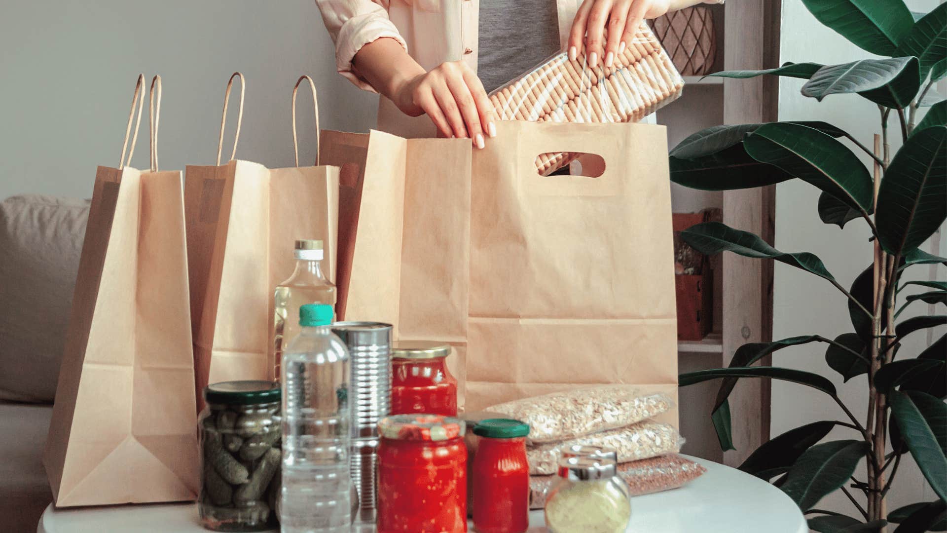 woman unpacking grocery bag of canned items