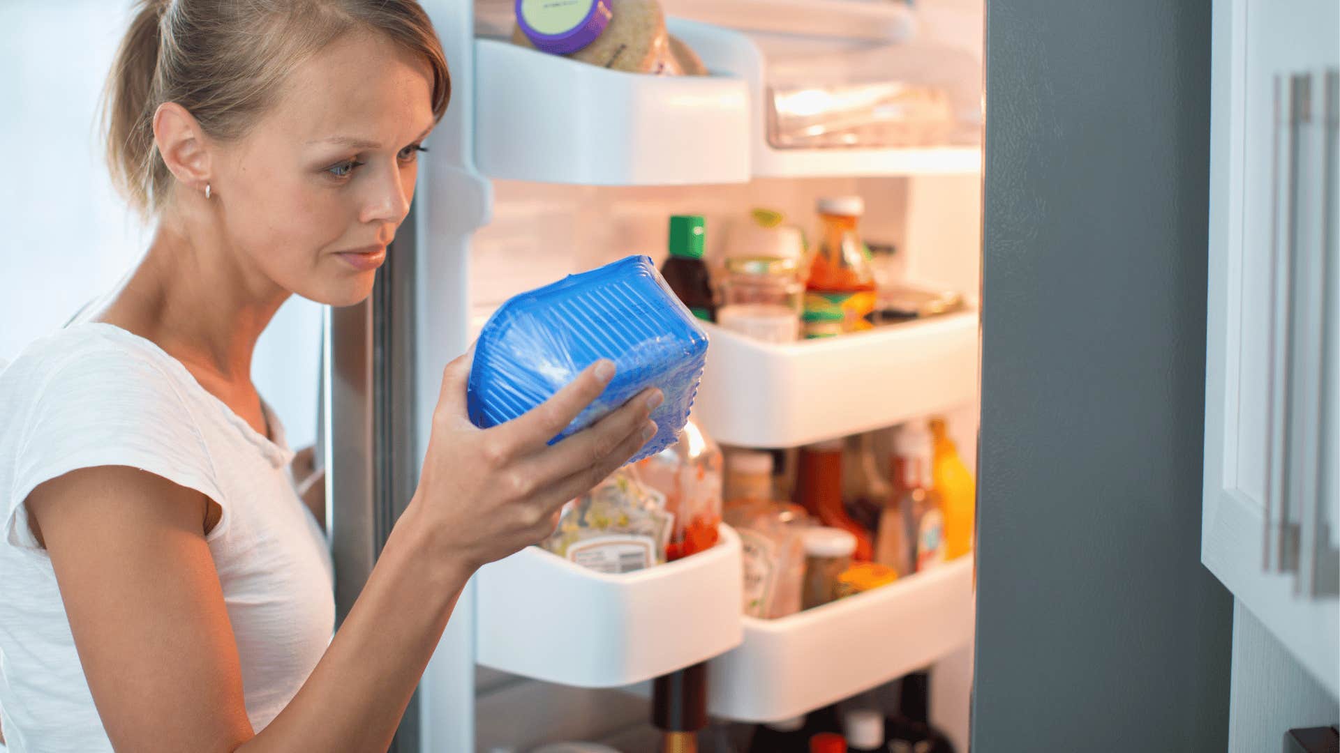 woman looking at expired food in her fridge