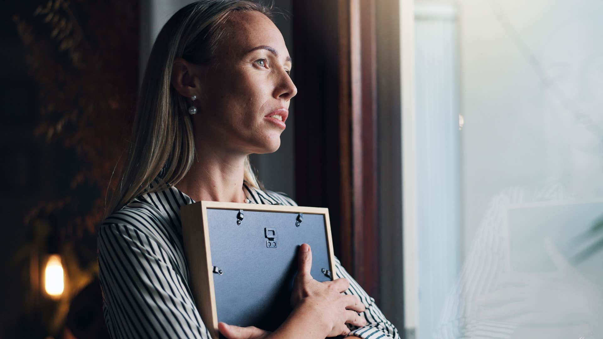 woman holding empty picture frame against chest