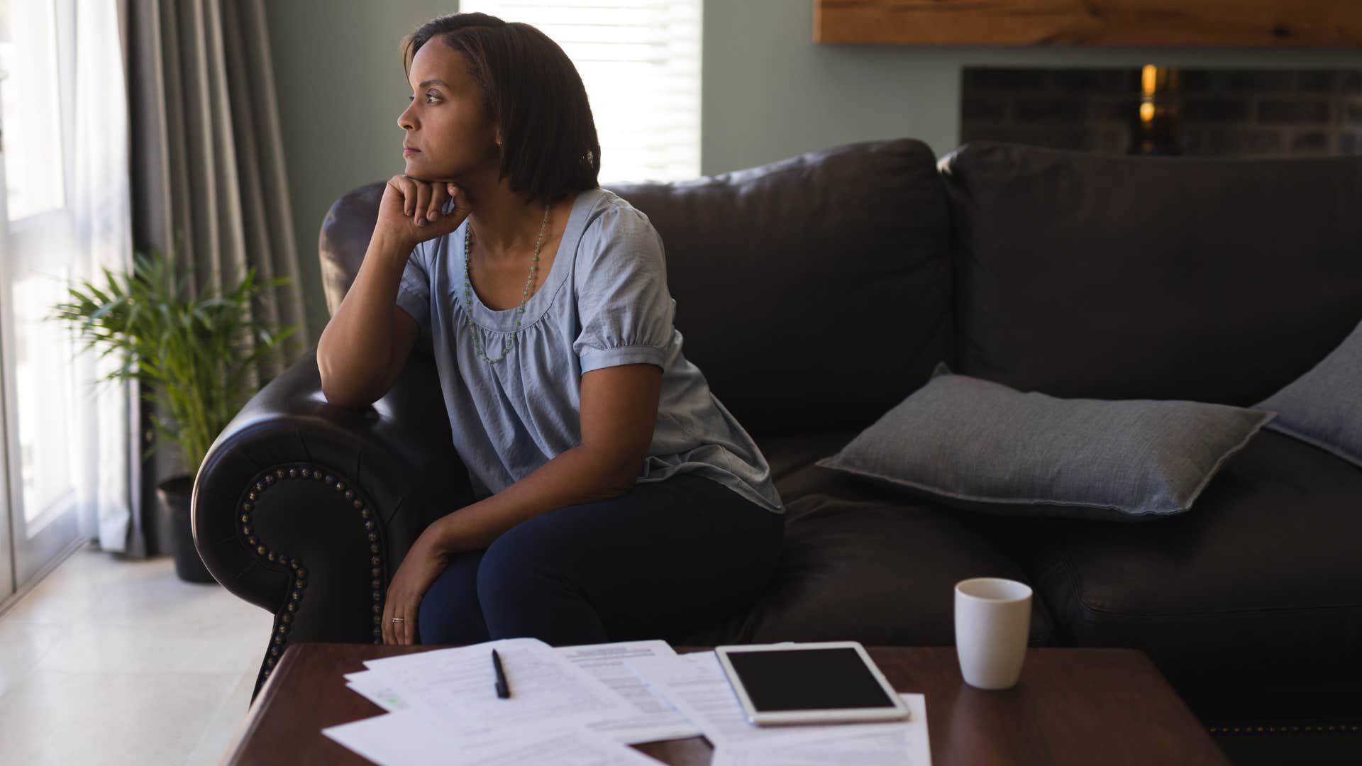 thoughtful woman sitting on couch in living room at home