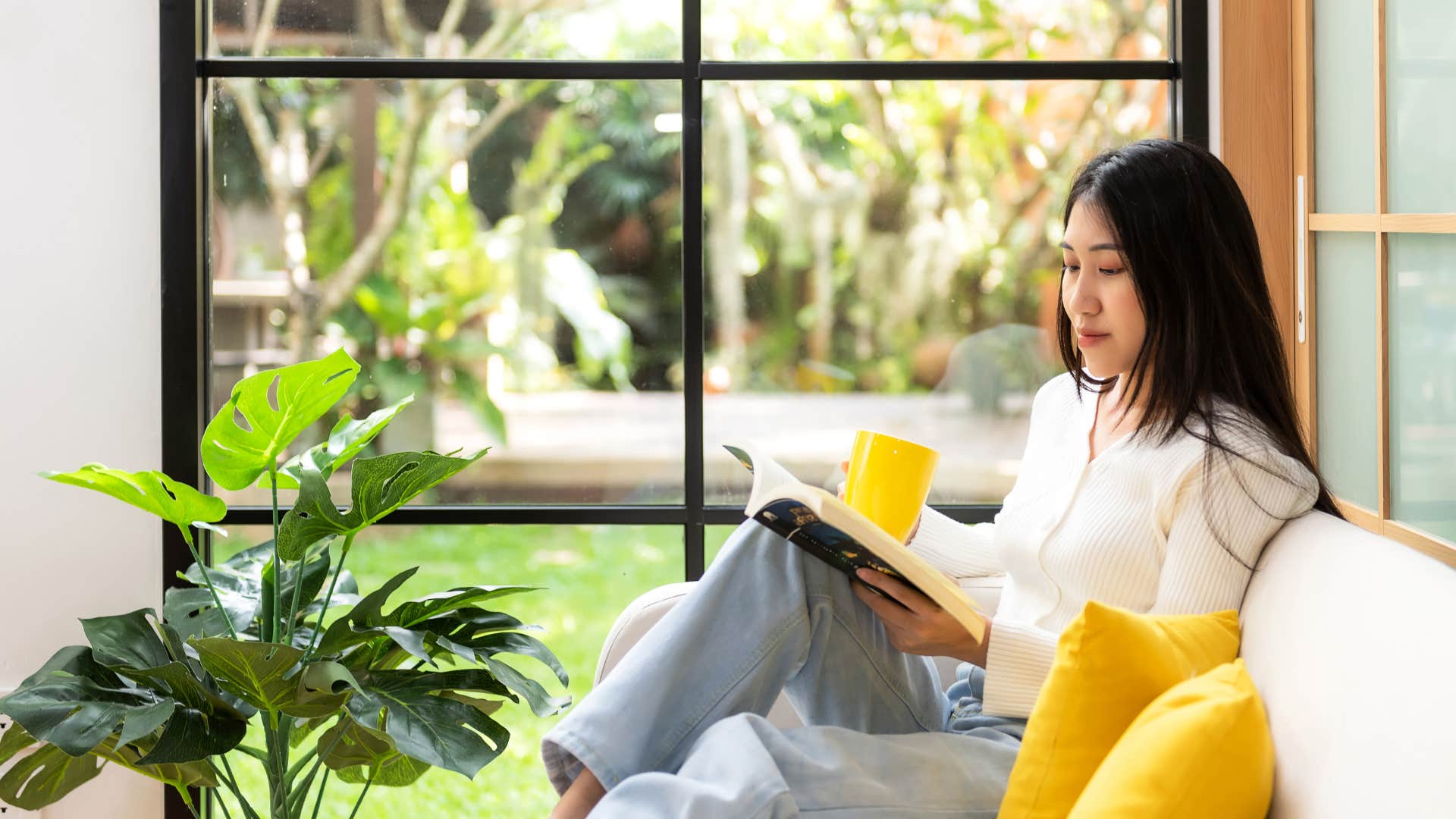 woman reading book on couch at home