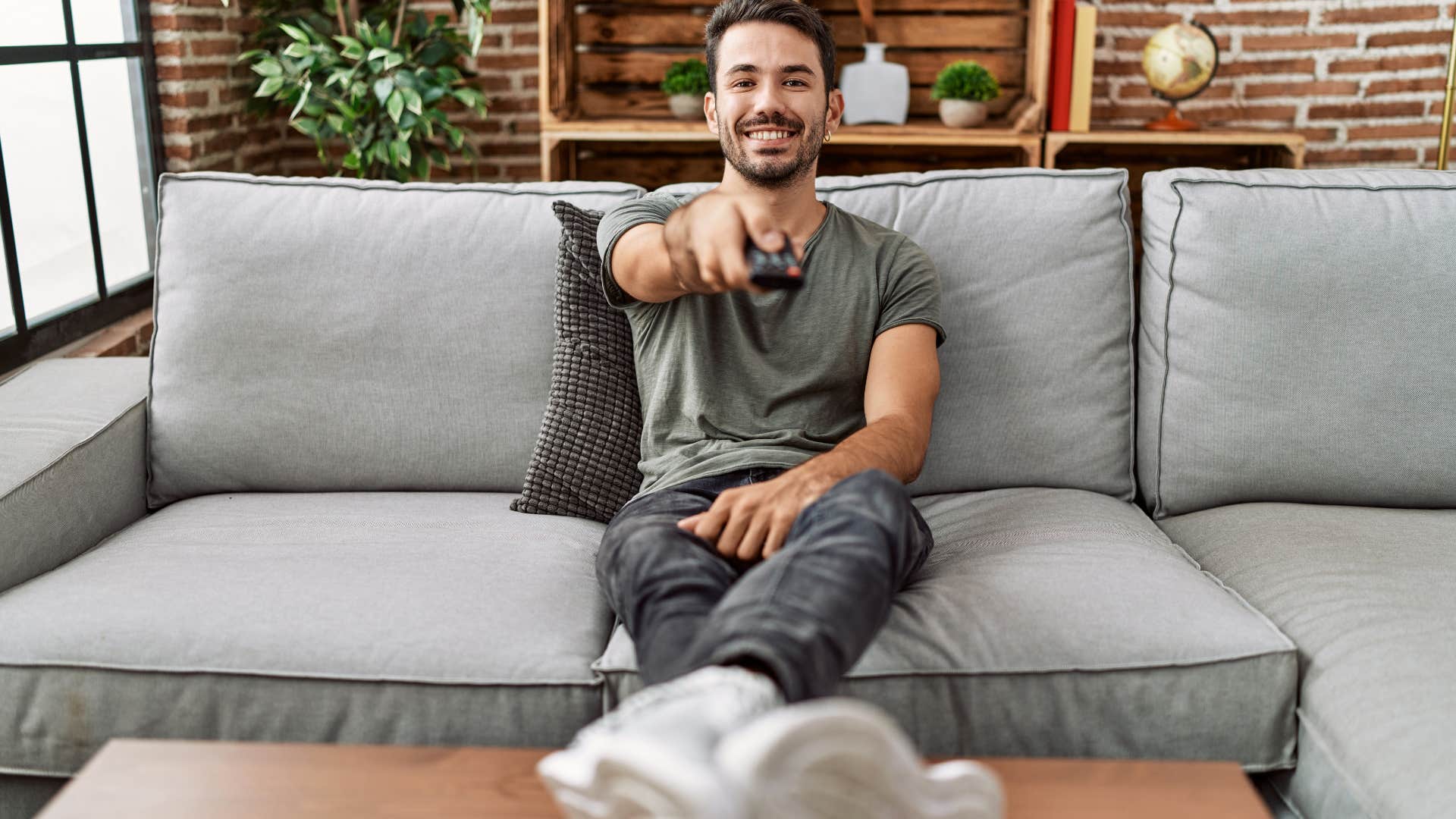 man sitting and turning on TV