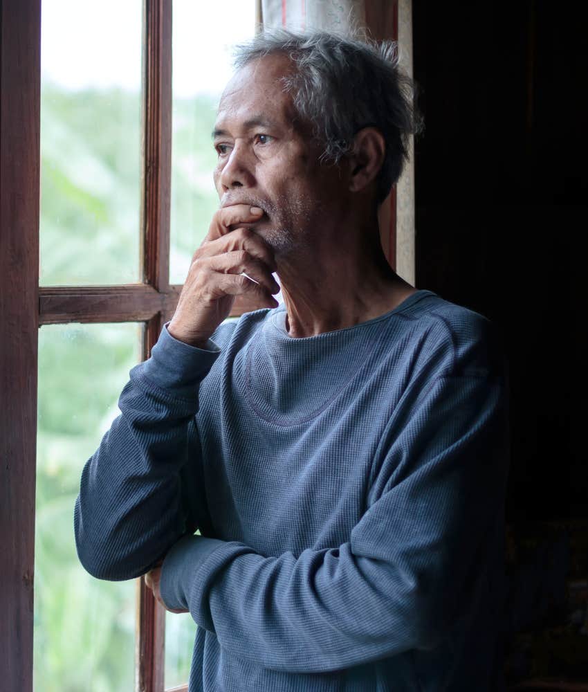 Introspective elder looks out window showing meaningful arc of life