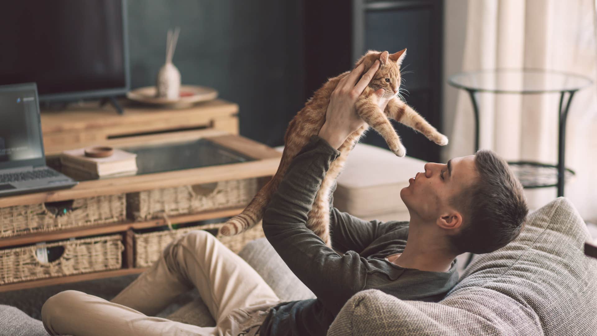 man holding up cat lovingly